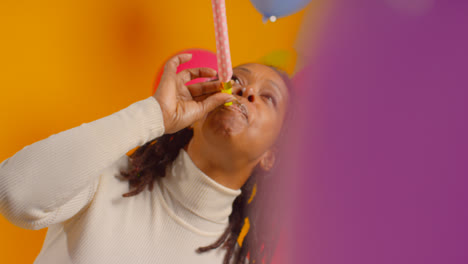 Studioporträt-Einer-Frau-Mit-Geburtstagsstirnband,-Die-Mit-Luftballons-Und-Partygebläse-Feiert-1